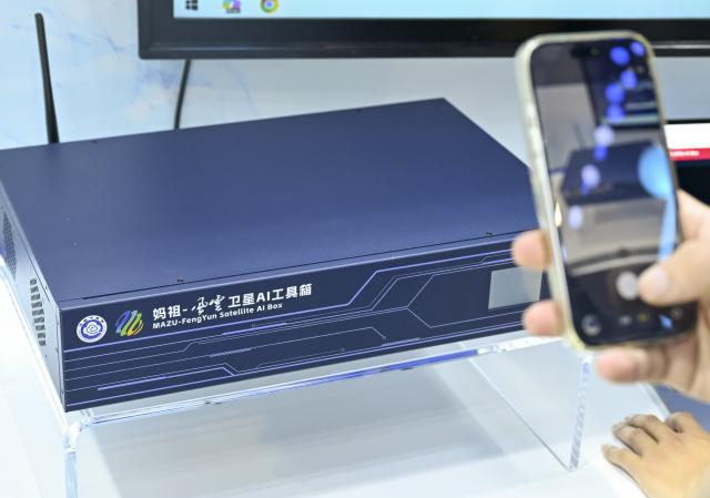 (260719) -- SHANGHAI, July 19, 2026 (Xinhua) -- A visitor takes photos of a MAZU-FengYun satellite AI box during the 2026 World AI Conference and High-Level Meeting on Global AI Governance in Shanghai, east China, July 19, 2026. The event scheduled from Friday to Monday showcases exhibitions of a number of AI agent hardware and system products, highlighting the transition of next-generation AI from a tool to an intelligent partner, empowering various industries and everyday life. (Xinhua/Chen Haoming)