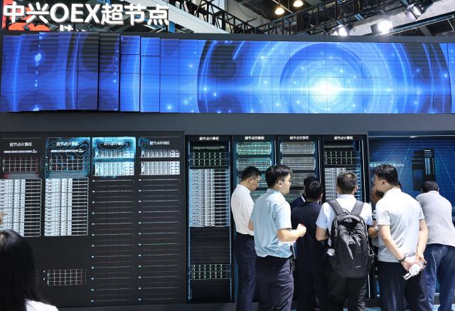 (260719) -- SHANGHAI, July 19, 2026 (Xinhua) -- People talk in front of the OEX supernode of ZTE displayed during the 2026 World AI Conference and High-Level Meeting on Global AI Governance in Shanghai, east China, July 17, 2026. The 2026 World AI Conference (WAIC) and High-Level Meeting on Global AI Governance opened here on Friday. A group of domestic supernode products draw public attentions during the event. (Xinhua/Fang Zhe)
