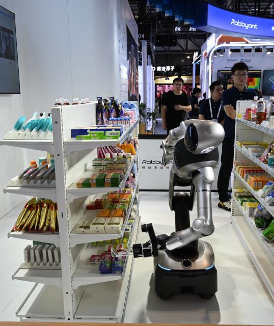 (260719) -- SHANGHAI, July 19, 2026 (Xinhua) -- A robot fetches a pack of mock medicine from a shelf during the 2026 World AI Conference in Shanghai, east China, July 19, 2026. The ongoing 2026 World AI Conference turns out to be a highly competitive arena for general embodied AI products from more than 200 providers. It refers to a general-purpose intelligence system that enables robots to perform variable tasks and adapt to different application scenarios. (Xinhua/Huang Xiaoyong)
