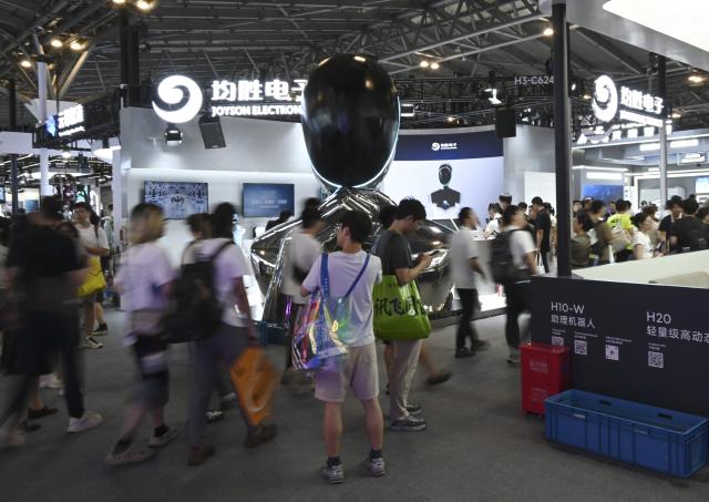 (260719) -- SHANGHAI, July 19, 2026 (Xinhua) -- Visitors are seen in front of a robot company's booth during the 2026 World AI Conference in Shanghai, east China, July 19, 2026. The ongoing 2026 World AI Conference turns out to be a highly competitive arena for general embodied AI products from more than 200 providers. It refers to a general-purpose intelligence system that enables robots to perform variable tasks and adapt to different application scenarios. (Xinhua/Huang Xiaoyong)