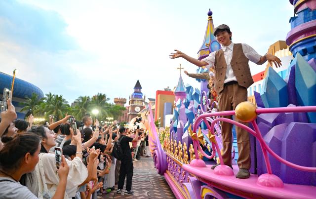 (260720) -- HAIKOU, July 20, 2026 (Xinhua) -- Tourist watch a parade during a carnival held at a themed park in Haikou, south China's Hainan Province, July 18, 2026. Hainan is seeing a surge in visitors during the summer holiday season. (Xinhua/Guo Cheng)