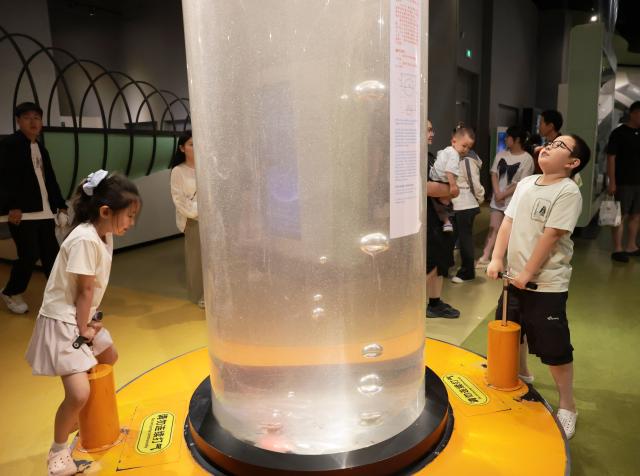 (260720) -- SHENYANG, July 20, 2026 (Xinhua) -- Visitors learn about liquid pressure through an exhibit at Liaoning Science and Technology Museum in Shenyang, northeast China's Liaoning Province, July 19, 2026.
  Many students came to Liaoning Science and Technology Museum during the summer holiday season to boost their scientific literacy through interactive exhibits and hands-on science experiments. (Xinhua/Li Gang)