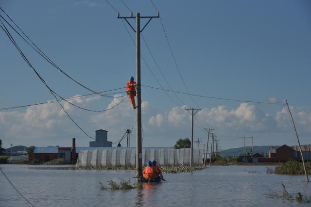 (260720) -- MUDANJIANG, July 20, 2026 (Xinhua) -- Staff members inspect power lines for electricity restoration in Ning'an Township of Ning'an City, Mudanjiang, northeast China's Heilongjiang Province, July 20, 2026. Water supply and power departments in Mudanjiang have stepped up efforts to restore water and electricity services in the affected areas as flooding gradually recedes in the city. (Photo by Zhang Chunxiang/Xinhua)