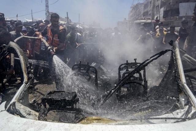 (260720) -- GAZA, July 20, 2026 (Xinhua) -- A firefighter extinguishes fire on a burned vehicle following an Israeli drone strike in Gaza City, on July 20, 2026. A drone struck a civilian vehicle in central Gaza City, injuring 14 people, including women and children, a source with the ambulance and emergency services told Xinhua. Four Palestinians were killed on Monday in two Israeli drone strikes targeting vehicles in the Gaza Strip, according to Palestinian security and medical sources. (Photo by Rizek Abdeljawad/Xinhua)