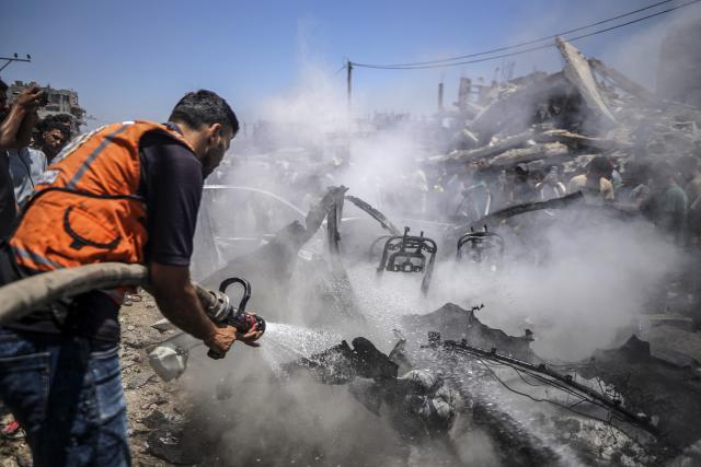 (260720) -- GAZA, July 20, 2026 (Xinhua) -- A firefighter extinguishes fire on a burned vehicle following an Israeli drone strike in Gaza City, on July 20, 2026. A drone struck a civilian vehicle in central Gaza City, injuring 14 people, including women and children, a source with the ambulance and emergency services told Xinhua. Four Palestinians were killed on Monday in two Israeli drone strikes targeting vehicles in the Gaza Strip, according to Palestinian security and medical sources. (Photo by Rizek Abdeljawad/Xinhua)