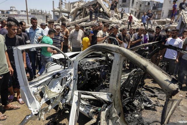 (260720) -- GAZA, July 20, 2026 (Xinhua) -- Palestinians stand around a burned vehicle following an Israeli drone strike in Gaza City, on July 20, 2026. A drone struck a civilian vehicle in central Gaza City, injuring 14 people, including women and children, a source with the ambulance and emergency services told Xinhua. Four Palestinians were killed on Monday in two Israeli drone strikes targeting vehicles in the Gaza Strip, according to Palestinian security and medical sources. (Photo by Rizek Abdeljawad/Xinhua)