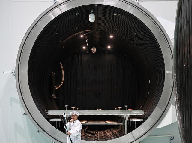 (260721) -- WUXI, July 21, 2026 (Xinhua) -- A journalist is seen near a thermal vacuum simulator at Guoyu Starry Sky Technology Co., Ltd. in the high-tech zone of Wuxi, east China's Jiangsu Province, July 20, 2026. Guoyu Starry Sky Technology Co., Ltd. specializes in the design and manufacturing of satellites. Its intelligent production line for commercial satellites can produce more than 150 units annually, each weighing between 200 kg and 500 kg. (Xinhua/Chen Yehua)