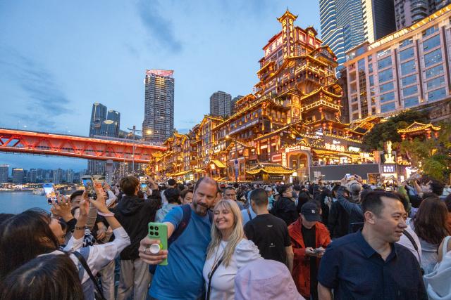 (260721) -- SHANGHAI, July 21, 2026 (Xinhua) -- Overseas tourists take selfies in front of the Hongyadong Scenic Area in Yuzhong District of Chongqing, southwest China, April 22, 2026. (Xinhua/Huang Wei)