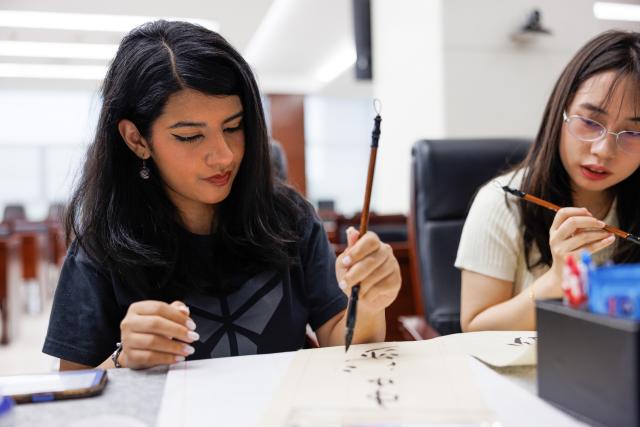 (260721) -- TIANJIN, July 21, 2026 (Xinhua) -- Rimaz Dakhilallah Aljohani experiences Chinese calligraphy at a cultural exchange event organized by Offshore Oil Engineering Co., Ltd. (COOEC) in Tianjin, north China, July 18, 2026. Rimaz Dakhilallah Aljohani, a 22-year-old junior majoring in petroleum engineering at King Fahd University of Petroleum and Minerals (KFUPM) in Saudi Arabia, began a two-month internship and training program with six of her classmates at Offshore Oil Engineering Co., Ltd. (COOEC) in Tianjin during the summer vacation. 
  At the Tianjin Intelligent Manufacturing Branch of COOEC, she has experienced modern welding through VR technology, and learned about technologies behind China's modular construction and manufacturing of offshore oil and gas equipment.
  In 2022, China and Saudi Arabia signed the implementation plan for the synergy between the Belt and Road Initiative and Saudi Arabia's Vision 2030. The KFUPM-COOEC internship program represents a concrete practice in implementing the plan and provides a platform for youth exchanges.
  "The level of intelligent manufacturing and standardized project management here has greatly impressed me," Rimaz said. "I truly value this opportunity for international practical training. It has allowed me to gain first-hand knowledge of China's experience in the offshore oil industry. I hope to bring what I have learned back to Saudi Arabia and contribute to China-Saudi Arabia energy cooperation." (Photo by Li Haowei/Xinhua)