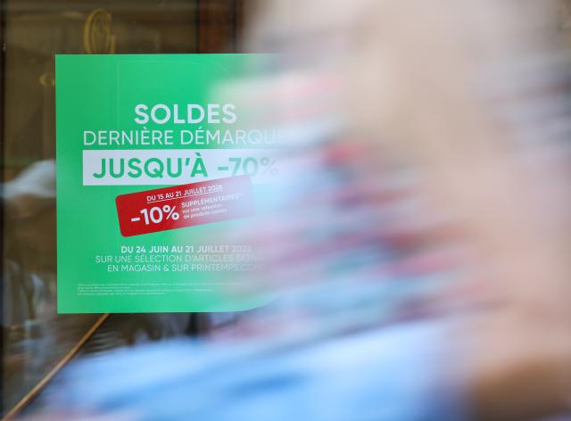 (260721) -- PARIS, July 21, 2026 (Xinhua) -- People walk past sale advertisements of a shop in Paris, France, on July 21, 2026. France's 2026 summer sales had been extended by one week to July 28 after a heatwave kept customers away from stores. (Xinhua/Wu Huiwo)