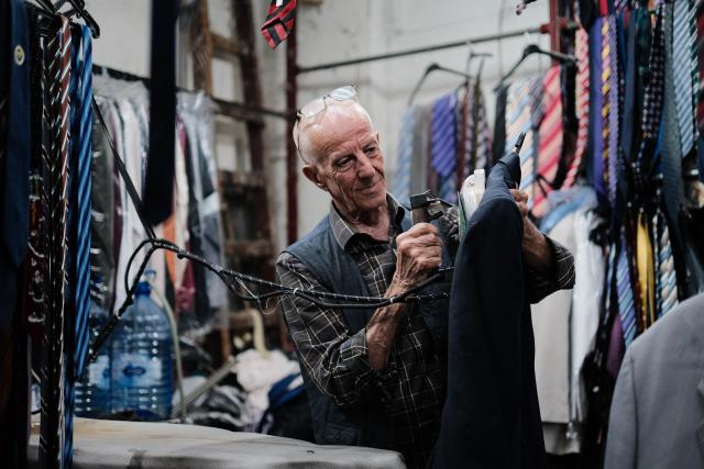 (260722) -- AMMAN, July 22, 2026 (Xinhua) -- A man irons clothes at a shop in the old city of Amman, Jordan, on July 21, 2026. Amman is the capital of Jordan where tradition and modernity coexist. From the ancient Citadel to the modern shopping district, traces of different eras intertwine to reveal the city's unique charm and enduring vitality. (Xinhua/Xin Mengchen)