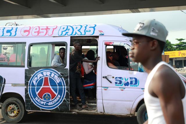 (260722) -- ABIDJAN, July 22, 2026 (Xinhua) -- A minibus conductor (2nd L) calls for passengers in Abidjan, Cote d'Ivoire, on July 21, 2026. Colorful minibuses serve as a primary mode of transport and a vibrant element of local street culture in Abidjan, the economic capital of Cote d'Ivoire. (Photo by Yvan Sonh/Xinhua)