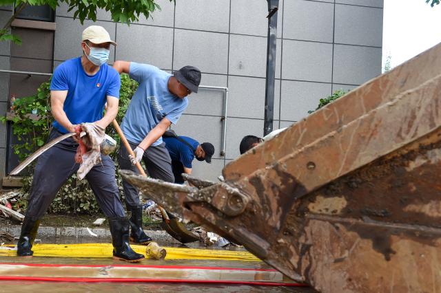 (260722) -- DUNHUA, July 22, 2026 (Xinhua) -- Officials from Dunhua education bureau remove garbage at a residential compound in Dunhua, Yanbian Korean Autonomous Prefecture, northeast China's Jilin Province, July 20, 2026. Flood recovery efforts were underway after the city was hit by flooding caused by a typhoon. (Xinhua/Zhang Nan)