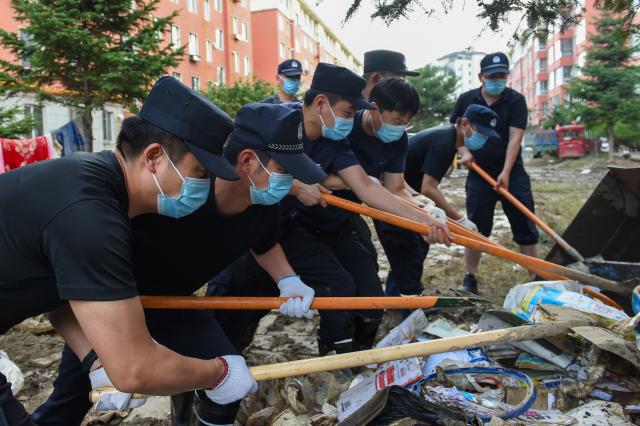 (260722) -- DUNHUA, July 22, 2026 (Xinhua) -- Police officers remove garbage at a residential compound in Dunhua, Yanbian Korean Autonomous Prefecture, northeast China's Jilin Province, July 20, 2026. Flood recovery efforts were underway after the city was hit by flooding caused by a typhoon. (Xinhua/Zhang Nan)