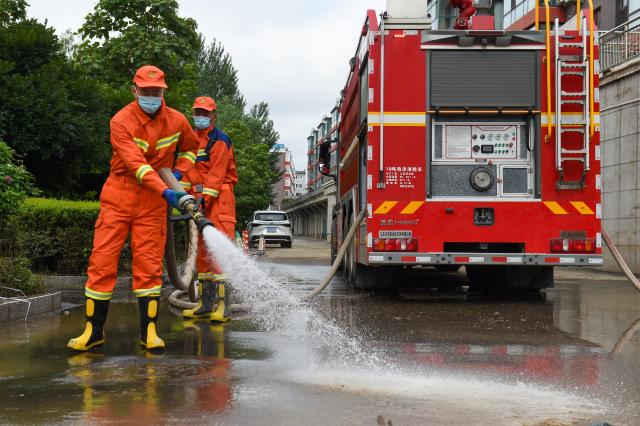 (260722) -- DUNHUA, July 22, 2026 (Xinhua) -- Firefighters clear sludge at a residential compound in Dunhua, Yanbian Korean Autonomous Prefecture, northeast China's Jilin Province, July 21, 2026. Flood recovery efforts were underway after the city was hit by flooding caused by a typhoon. (Xinhua/Zhang Nan)