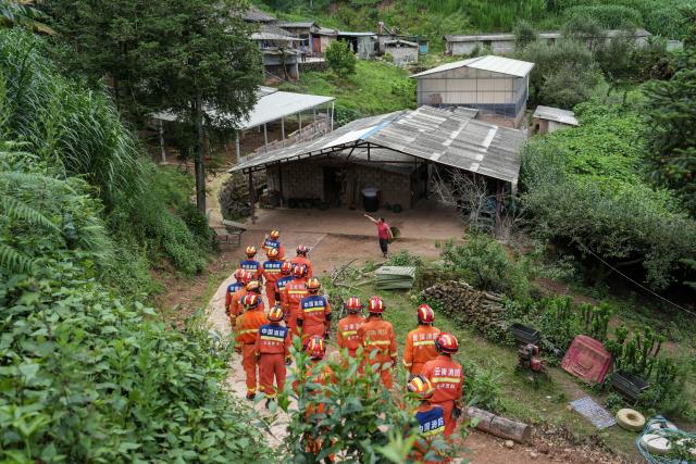 (260722) -- MOJIANG, July 22, 2026 (Xinhua) -- Firefighters walk to check affected houses at Jingping Village in Yutang Town of Mojiang Hani Autonomous County, southwest China's Yunnan Province, on July 22, 2026. The Yunnan provincial earthquake relief headquarters has activated a Level-IV emergency response after a 5.0-magnitude earthquake jolted Mojiang on Tuesday, local authorities said.
   No casualties have been reported so far. (Xinhua/Chen Xinbo)