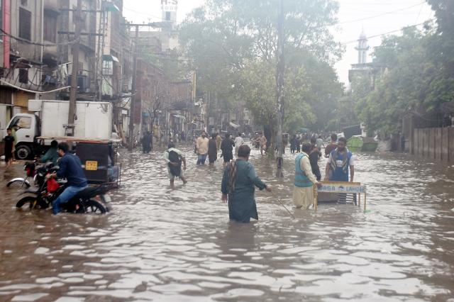 (260722) -- LAHORE, July 22, 2026 (Xinhua) -- People wade through a flooded street after heavy monsoon rains in Lahore, Pakistan, July 22, 2026.
  At least eight people were killed and 16 others injured in rain-related incidents across Pakistan over the past 24 hours as monsoon showers continued to batter parts of the country, the National Disaster Management Authority said on Tuesday. (Photo by Sajjad/Xinhua)