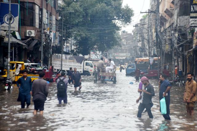 (260722) -- LAHORE, July 22, 2026 (Xinhua) -- People wade through a flooded street after heavy monsoon rains in Lahore, Pakistan, July 22, 2026.
  At least eight people were killed and 16 others injured in rain-related incidents across Pakistan over the past 24 hours as monsoon showers continued to batter parts of the country, the National Disaster Management Authority said on Tuesday. (Photo by Sajjad/Xinhua)