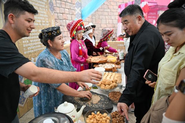 (260723) -- BEIJING, July 23, 2026 (Xinhua) -- Visitors taste specialty snacks during the 12th Manas international cultural tourism festival in Akto County, Kirgiz Autonomous Prefecture of Kizilsu in northwest China's Xinjiang Uygur Autonomous Region, July 13, 2026. (Xinhua/Ding Lei)