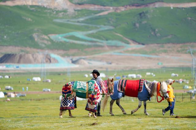 (260723) -- AMDO, July 23, 2026 (Xinhua) -- Local residents lead their horses on the grassland in Amdo County, southwest China's Xizang Autonomous Region, July 22, 2026. The horse racing competition kicked off here on Thursday, featuring vibrant performances and horse racing events. (Xinhua/Tenzin Nyida)
