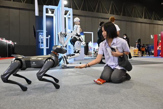 (260723) -- BANGKOK, July 23, 2026 (Xinhua) -- A visitor interacts with a robotic dog at Thailand-China Cooperation Expo 2026 in Bangkok, Thailand, July 22, 2026. TO GO WITH "Roundup: Thailand-China expo kicks off in Bangkok to expand multi-sector cooperation" (Xinhua/Rachen Sageamsak)