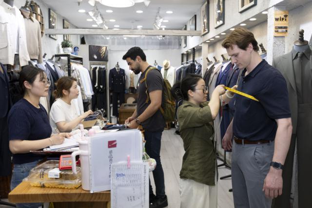 (260723) -- SHANGHAI, July 23, 2026 (Xinhua) -- A tourist from the United States gets measured for custom-made suits at a clothing store in Shanghai, east China, July 22, 2026. The foreign visitors entering Shanghai increased 22 percent year on year in the first half of 2026, thanks to the country's expanding visa exemption policies. 
  Chinese designer products have emerged as a new driver of inbound consumption. Rather than buying only traditional Chinese specialties such as tea and silk, overseas visitors are increasingly following shopping tips on social media to seek out bags, footwear, clothing and other products by Chinese designers. (Xinhua/Wang Xiang)
