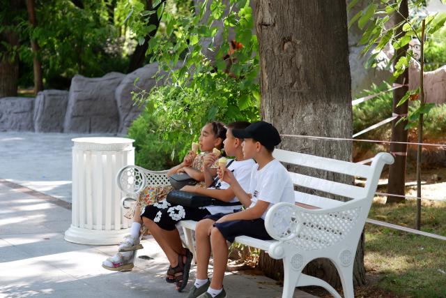 (260724) -- ASHGABAT, July 24, 2026 (Xinhua) -- Children enjoy ice creams to cool off amid a heatwave at Ashgabat Park in Ashgabat, Turkmenistan, July 23, 2026. (Photo by Cui Jiaxin/Xinhua)