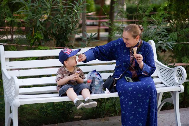 (260724) -- ASHGABAT, July 24, 2026 (Xinhua) -- A woman wipes a child's face as they enjoy ice creams to cool off amid a heatwave at Ashgabat Park in Ashgabat, Turkmenistan, July 23, 2026. (Photo by Cui Jiaxin/Xinhua)