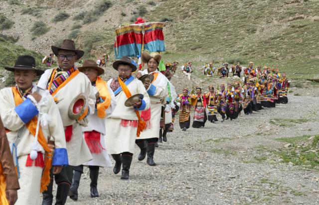 (260724) -- SHANNAN, July 24, 2026 (Xinhua) -- Farmers dressed in traditional attire parade around a farmland during the Ongkor Festival at Tashi Chodan Community in Shannan, southwest China's Xizang Autonomous Region, July 24, 2026. The Tashi Chodan Community in Shannan celebrated the annual Ongkor Festival, a national intangible cultural heritage, on Friday. Local people paraded around the farmland to pray for a bumper harvest during the festival, whose specific date varies according to the ripening time of crops in different regions. (Xinhua/Jigme Dorje)
