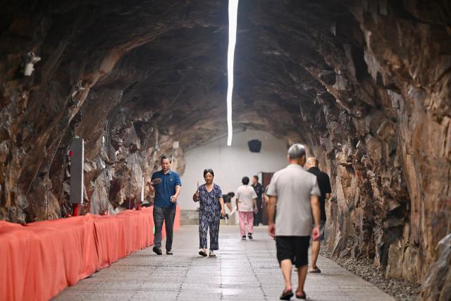 (260724) -- FUZHOU, July 24, 2026 (Xinhua) -- Residents relax at an air-raid shelter to cool off in Fuzhou, southeast China's Fujian Province, July 23, 2026. As summer temperatures soar, Fuzhou has made some tunnels, air-raid shelters and metro stations available as public cooling spaces. Equipped with benches, chairs and other convenience facilities, these sites have become popular for residents to relax and escape the heat. (Xinhua/Jiang Kehong)