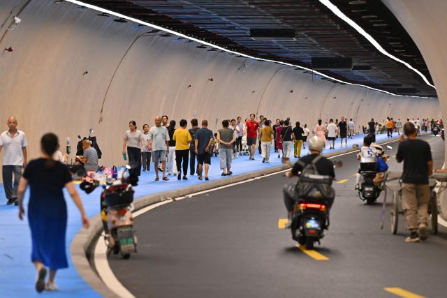 (260724) -- FUZHOU, July 24, 2026 (Xinhua) -- Residents relax in a tunnel to cool off in Fuzhou, southeast China's Fujian Province, July 18, 2026. As summer temperatures soar, Fuzhou has made some tunnels, air-raid shelters and metro stations available as public cooling spaces. Equipped with benches, chairs and other convenience facilities, these sites have become popular for residents to relax and escape the heat. (Xinhua/Jiang Kehong)