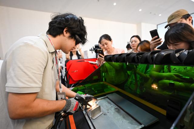 (260724) -- SUZHOU, July 24, 2026 (Xinhua) -- A staff member grips a welding gun weighing just 300 grams at Suzhou Maxphotonics Technology Co., Ltd. in Suzhou, east China's Jiangsu Province, July 22, 2026. TO GO WITH "Economic Watch: Photonics industry thrives in east China's Suzhou" (Xinhua/Chen Yehua)