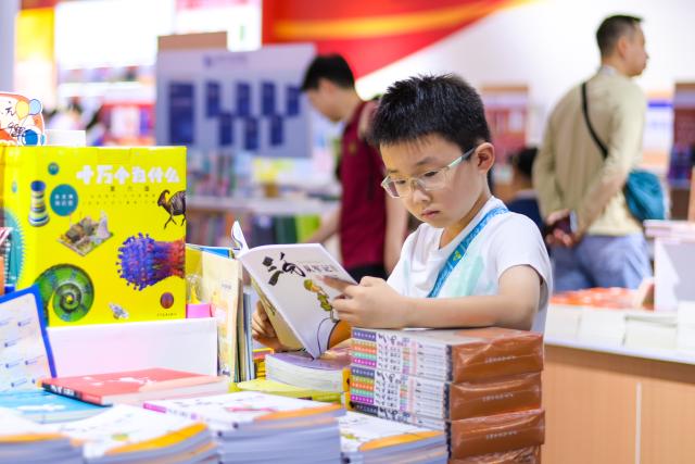 (260725) -- BEIJING, July 25, 2026 (Xinhua) -- A child reads a book at the 34th National Book Expo in Hangzhou, east China's Zhejiang Province, July 24, 2026. The event kicked off here on Friday with nearly a million publications of various types on display, either online or on site. (Xinhua/Jiang Han)