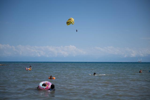 (260725) -- ISSYK-KUL LAKE, July 25, 2026 (Xinhua) -- People enjoy themselves at Issyk-Kul Lake in Kyrgyzstan, on July 23, 2026. Issyk-Kul Lake, located in the northeastern part of Kyrgyzstan, covers an area of more than 6,000 square kilometers and ranks as the world's second-largest alpine lake. (Xinhua/Li Renzi)