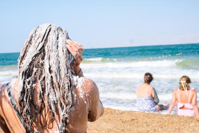 (260726) -- AMMAN, July 26, 2026 (Xinhua) -- A tourist applies Dead Sea salt to her hair near the Dead Sea in Jordan, on July 25, 2026. The Dead Sea has been experiencing a long-term decline in its water level due to reduced inflow from the Jordan River, the region's naturally high evaporation rates, and industrial mineral extraction. Available data show that as of July 2026, the Dead Sea's surface was approximately 440 meters below sea level, and its water level has been declining by an average of more than one meter annually. (Xinhua/Xin Mengchen)