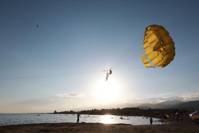 (260726) -- BEIJING, July 26, 2026 (Xinhua) -- People enjoy themselves at Issyk-Kul Lake in Kyrgyzstan, on July 24, 2026. Issyk-Kul Lake, located in the northeastern part of Kyrgyzstan, covers an area of more than 6,000 square kilometers and ranks as the world's second-largest alpine lake. (Photo by Roman/Xinhua)