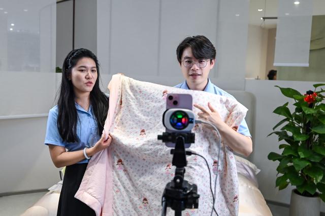 (260726) -- YANCHENG, July 26, 2026 (Xinhua) -- Employees promote products via live-streaming in Jiangsu Yueda Textile Group Co., Ltd. in Yancheng City, east China's Jiangsu Province, July 25, 2026. Jiangsu Yueda Textile Group Co., Ltd. has been recognized as a "Global Lighthouse Factory" due to its recent advancements in intelligent, digital, and green transformations, which have enhanced production efficiency and product quality.
  In recent years, Yancheng has focused on intelligent manufacturing and industrial upgrading in its industrial enterprises. By promoting technological innovation and optimizing the industrial chain, the city has forged a new path of high-quality development. (Xinhua/Chen Yehua)