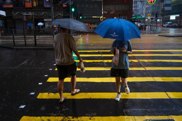 (260726) -- HONG KONG, July 26, 2026 (Xinhua) -- People walk amid rain in Hong Kong, south China, July 26, 2026. The Hong Kong Observatory downgraded the typhoon signal to the Strong Wind Signal No. 3 at 12:40 p.m. local time on Sunday as Typhoon Noul moves away.
   With Noul moving into inland Guangdong and weakening, local winds are decreasing gradually, according to the observatory. (Xinhua/Zhu Wei)