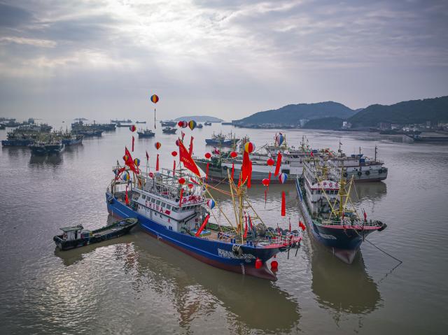 (260726) -- WENLING, July 26, 2026 (Xinhua) -- A drone photo taken on June 27, 2026 shows fishing boats docking at a wharf in Liruo Village of Shitang Town, Wenling City, east China's Zhejiang Province. Liruo is a village located in the southwestern part of Shitang Town, Wenling City. For generations, local residents have relied on the sea for their livelihood. The village is known for its distinctive stone constructions, which were built to withstand typhoons and other severe weather.
   Today, the ancient fishing village is boosting its cultural and tourism industries. Many traditional stone houses have been transformed into cafes and homestays, while fishing nets are crafted into handbags, serving as souvenirs for tourists together with other cultural and creative products. (Xinhua/Jiang Han)