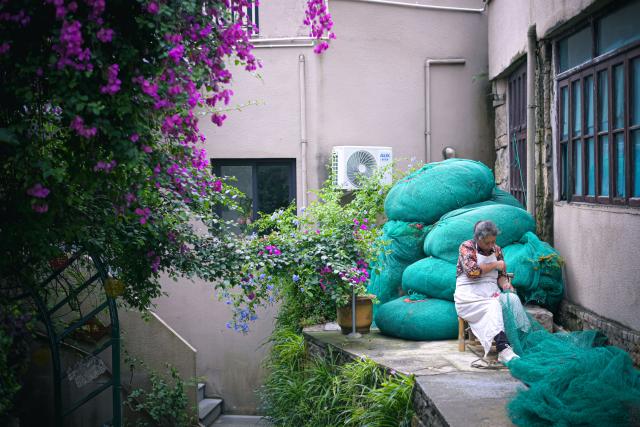 (260726) -- WENLING, July 26, 2026 (Xinhua) -- A villager fixes a fishing net in Liruo Village of Shitang Town, Wenling City, east China's Zhejiang Province, June 27, 2026. Liruo is a village located in the southwestern part of Shitang Town, Wenling City. For generations, local residents have relied on the sea for their livelihood. The village is known for its distinctive stone constructions, which were built to withstand typhoons and other severe weather.
   Today, the ancient fishing village is boosting its cultural and tourism industries. Many traditional stone houses have been transformed into cafes and homestays, while fishing nets are crafted into handbags, serving as souvenirs for tourists together with other cultural and creative products. (Xinhua/Jiang Han)