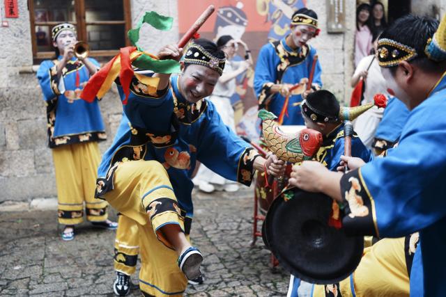 (260726) -- WENLING, July 26, 2026 (Xinhua) -- Actors perform Dazou drum, a national intangible cultural heritage, for tourists in Liruo Village of Shitang Town, Wenling City, east China's Zhejiang Province, June 28, 2026. Liruo is a village located in the southwestern part of Shitang Town, Wenling City. For generations, local residents have relied on the sea for their livelihood. The village is known for its distinctive stone constructions, which were built to withstand typhoons and other severe weather.
   Today, the ancient fishing village is boosting its cultural and tourism industries. Many traditional stone houses have been transformed into cafes and homestays, while fishing nets are crafted into handbags, serving as souvenirs for tourists together with other cultural and creative products. (Photo by Mo Chaoren/Xinhua)