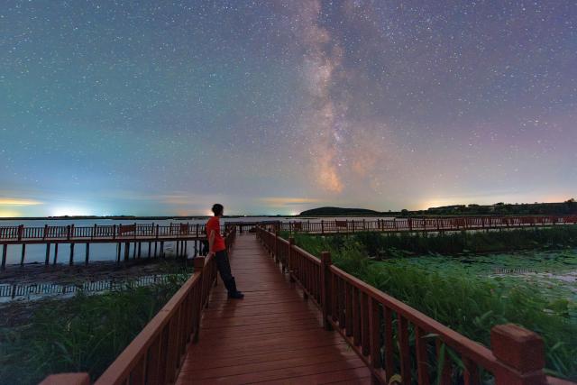 (260727) -- FUJIN, July 27, 2026 (Xinhua) -- This photo taken on July 17, 2026 shows the Milky Way over the Fujin National Wetland Park in Fujin City, northeast China's Heilongjiang Province. Thanks to years of ecological restoration, the Fujin National Wetland Park now features a thriving ecosystem and breathtaking natural beauty. (Photo by Qu Yubao/Xinhua)