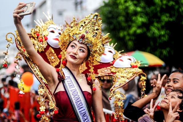 (260727) -- JEMBER, July 27, 2026 (Xinhua) -- A performer takes a selfie with spectators during the Jember Fashion Carnival 2026 in Jember, East Java, Indonesia, July 26, 2026. Held under the theme of Humanity, Earth, and Life (HEAL), this year's carnival highlights humanity, environmental sustainability, and the relationship between people and nature. (Photo by Sahlan Kurniawan/Xinhua)