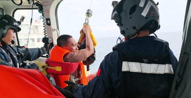 (260727) -- SOUTH CHINA SEA, July 27, 2026 (Xinhua) -- This image captured on July 27, 2026 shows a rescued crew member of Vietnamese vessel KHOI NGUYEN 18 being transferred from a Chinese rescue helicopter to a Vietnamese vessel, above the waters adjacent to Yongshu Jiao in China's Nansha Qundao in the South China Sea. China has rescued 47 of the 62 crew members after a Vietnamese ship sank on Friday night while operating in unfavorable weather conditions in the South China Sea, Chinese foreign ministry spokesperson Lin Jian said Monday.
   TO GO WITH "Column: Duty beyond dispute: maritime search and rescue in South China Sea" (Sansha Maritime Safety Administration/Handout via Xinhua)