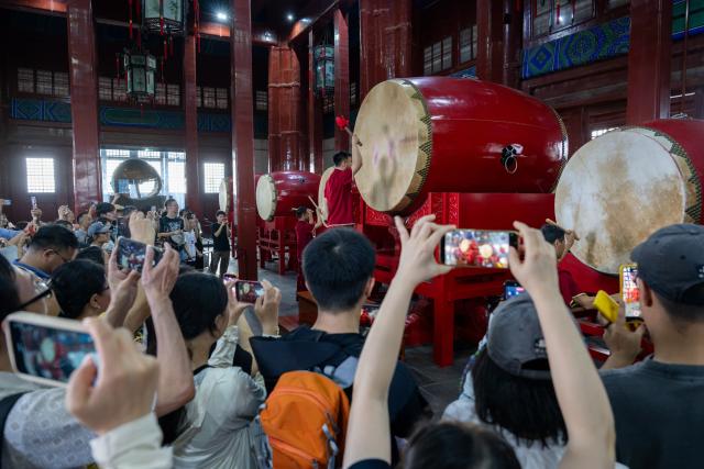 (260727) -- BEIJING, July 27, 2026 (Xinhua) -- People enjoy a performance at the Drum Tower in Beijing, capital of China, July 27, 2026. The second anniversary of the inscription of the Beijing Central Axis on the UNESCO World Heritage List falls on July 27.
   Since its inscription, the 7.8-kilometer-long axis has continued to gain new vitality, attracting more visitors to experience Beijing's historical heritage amid the blend of ancient architecture and modern life, while bringing World Heritage closer to everyday life.
   Stretching from the Bell and Drum Towers in the north to Yongdingmen Gate in the south, the Beijing Central Axis reflects traditional Chinese urban planning and serves as the spatial backbone of the old city. Carrying the history of Beijing's urban development, it bears witness to the continuity of Chinese civilization and reflects the capital's evolution through the ages. (Xinhua/Hu Jingwen)
