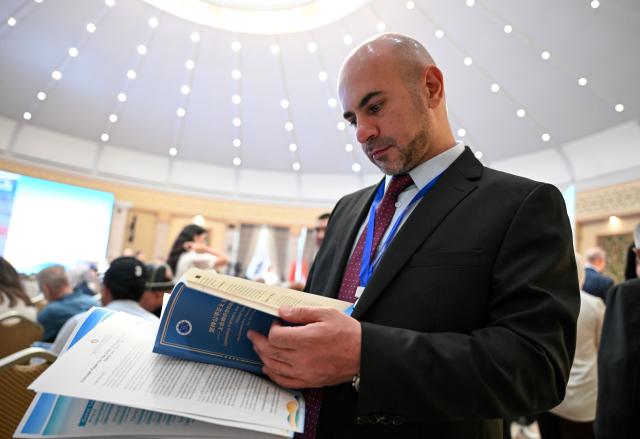 (260727) -- BISHKEK, July 27, 2026 (Xinhua) -- A participant reads a copy of the Xinhua think tank report titled "Upholding Fairness and Justice and Improving Global Governance -- Achievements, Opportunities, and Prospects for SCO Cooperation" at the 2026 Shanghai Cooperation Organization (SCO) Media and Think Tank Summit in Bishkek, Kyrgyzstan, July 27, 2026.
  The report, which was released here on Monday by the National High-Level Think Tank of Xinhua News Agency, offered a systematic review of the SCO's pioneering achievements and historic accomplishments over the past 25 years since its founding, an in-depth analysis of the broad opportunities for cooperation within the organization in the current international situation, and a comprehensive presentation of the broad prospects and global significance of building an SCO community with a shared future. (Xinhua/Feng Kaihua)
