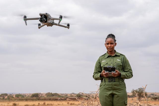(260728) -- KAJIADO, July 28, 2026 (Xinhua) -- A member of Team Lioness uses a drone to check the surrounding conditions at Ole Narika conservancy in Kajiado County, Kenya, July 22, 2026. TO GO WITH "Feature: All-female rangers boost wildlife conservation efforts in Kenya's Amboseli" (Xinhua/Xie Jianfei)