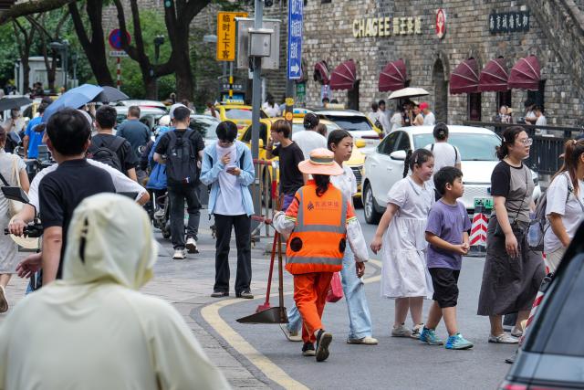 (260728) -- NANJING, July 28, 2026 (Xinhua) -- A sanitation worker in cooling vest walks on the street in Nanjing, east China's Jiangsu Province, July 28, 2026. Recently, in response to the high summer temperatures, sanitation workers in Xuanwu District of Nanjing City have been equipped with cooling vests. The vests are fitted with miniature fans on both sides of the waist, providing inward airflow. (Xinhua/Li Bo)