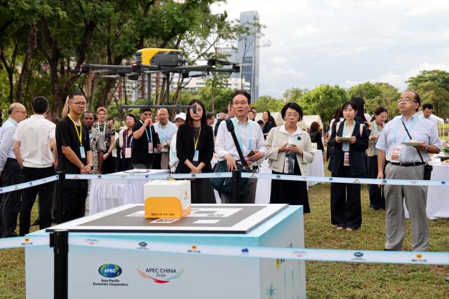 (260728) -- SHENZHEN, July 28, 2026 (Xinhua) -- Attendees of the 2026 APEC Ministerial Meeting on Forestry watch a drone delivering meal package at an ecological preservation stripe in Shenzhen, south China's Guangdong Province, July 28, 2026. The meeting was held in Shenzhen from July 27 to 28. (Xinhua/Liang Xu)