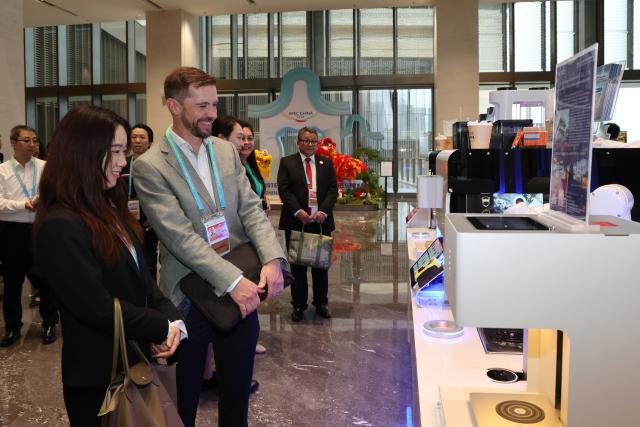 (260728) -- SHENZHEN, July 28, 2026 (Xinhua) -- Attendees watch a robotic barista demonstration outside the venue of the 2026 APEC Ministerial Meeting on Forestry in Shenzhen, south China's Guangdong Province, July 28, 2026. The meeting was held in Shenzhen from July 27 to 28. (Xinhua/Liang Xu)